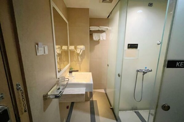 A hotel bathroom with a sink, mirror, towel rack, and shower. - Ke'erma Business Hotel (Zhongshan)