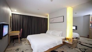 Ein Hotelzimmer mit Bett, Schreibtisch, Sessel, Nachttisch, Fernseher und einem großen Fenster mit Vorhängen.