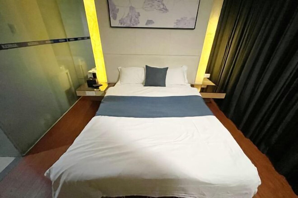 A hotel room with a bed, nightstands, a lamp, and a painting on the wall.