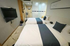 A hotel room with two beds, a flat-screen TV, a fan, and a whiteboard on the wall. - Ke'erma Business Hotel (Zhongshan)