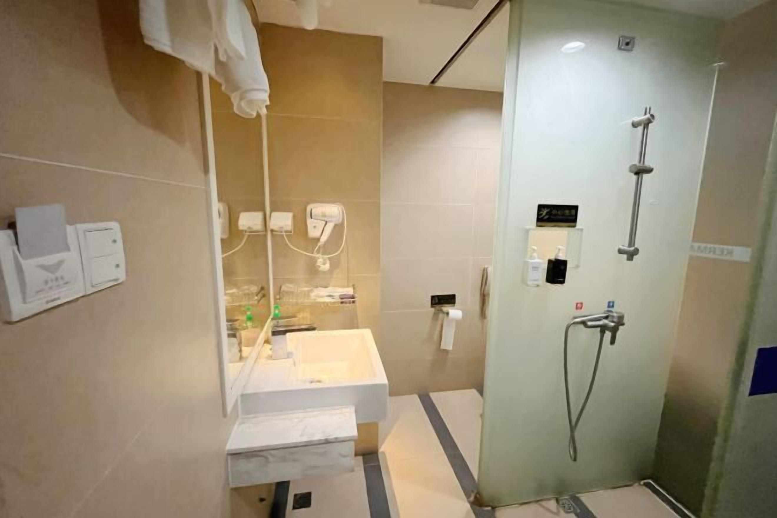 A modern bathroom with a glass shower enclosure, a white sink, and a mirror.