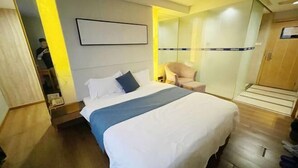 Una camera d'albergo con un letto, una sedia, un armadio e uno specchio.