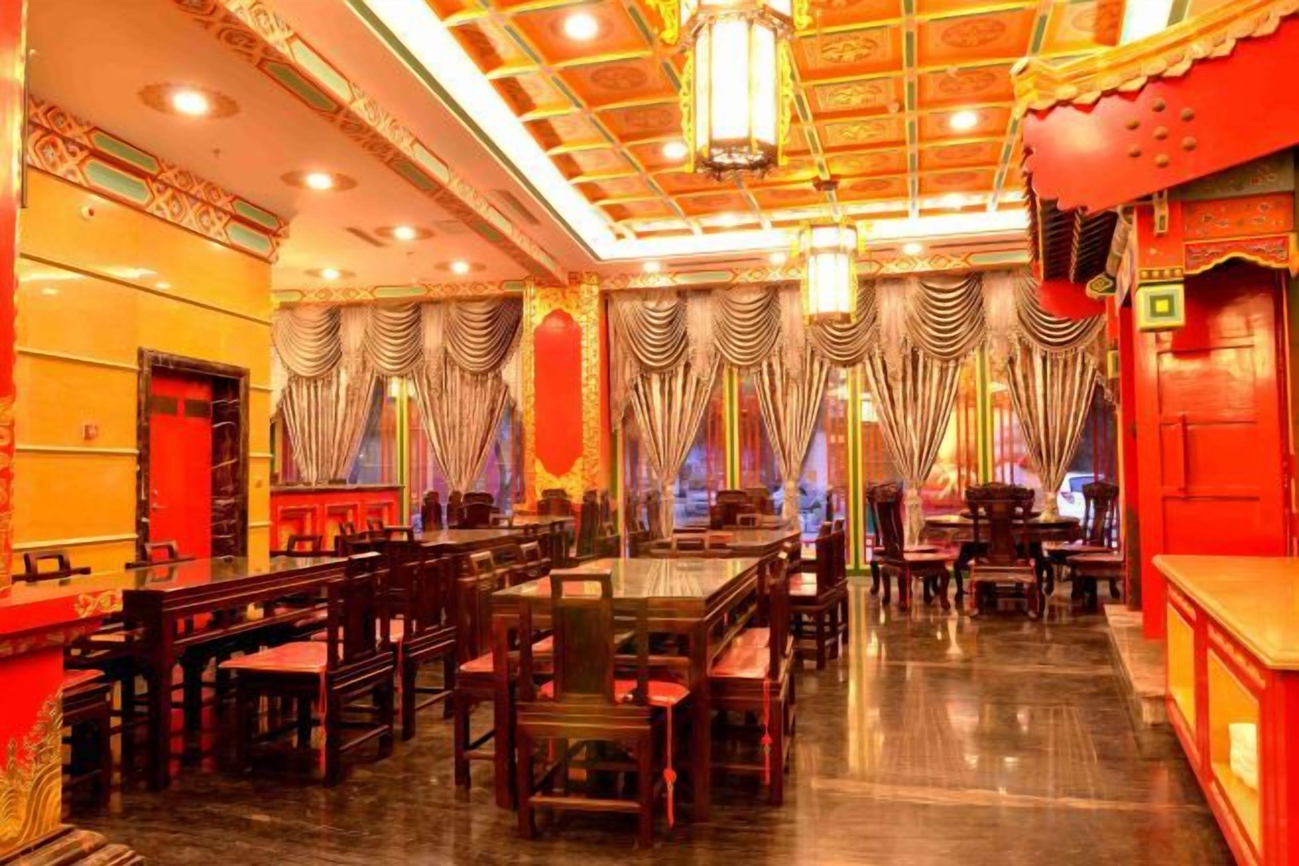 A spacious dining area with high ceilings, ornate chandeliers, and traditional drapery.