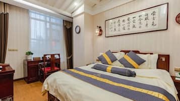 A hotel room with a bed, a desk, a chair, and a window.