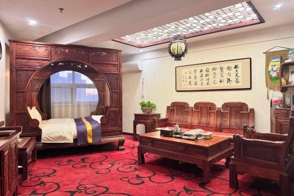 Une chambre traditionnelle avec un lit, un bureau en bois et une moquette rouge.