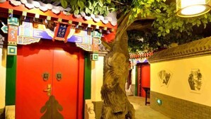 Ein traditionelles chinesisches Gebäude mit roten Türen, einer großen Baumskulptur und kulturellen Verzierungen.