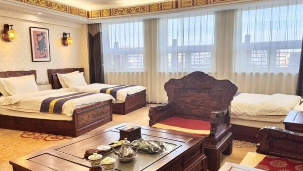 Ein Hotelzimmer mit zwei Betten, einem Holztisch mit Tee-Service und einem traditionellen Sessel.