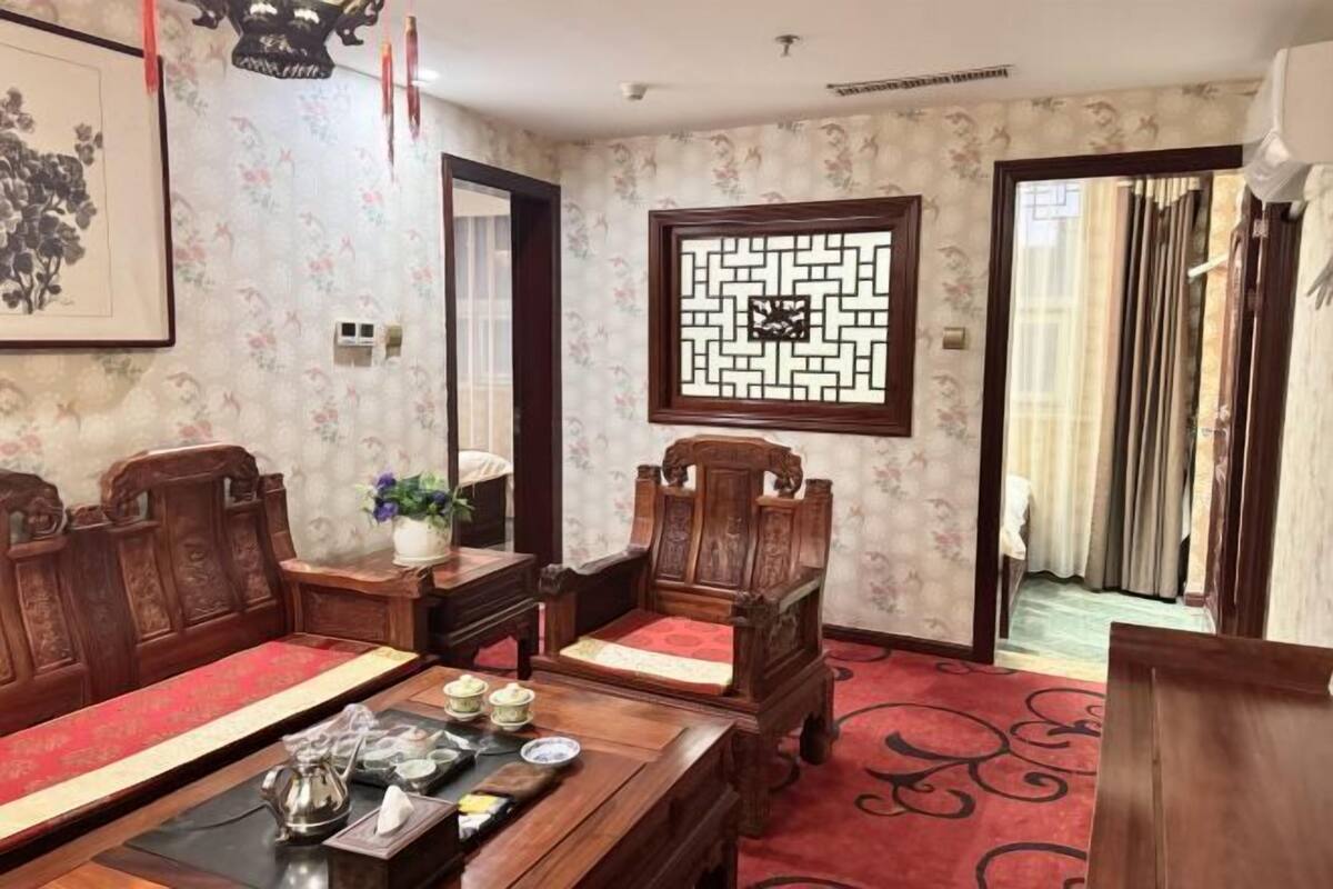 Une pièce au décor traditionnel, avec des meubles en bois, une moquette rouge et un paravent décoratif.