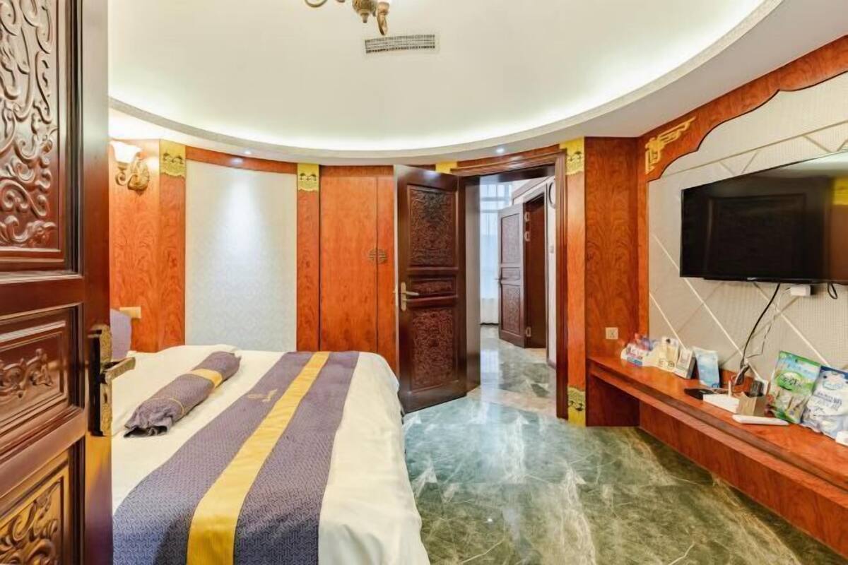 Une chambre d’hôtel comprenant un lit, une télévision, un comptoir de réception et une porte donnant sur une autre chambre.