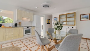 A modern kitchen with a glass dining table, grey chairs, and wooden cabinets. - Arundel - Javea, Costa Blanca (Javea)