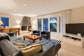Ein modernes Wohnzimmer mit Kamin, Fernseher und einem Essbereich mit Tisch und Stühlen.