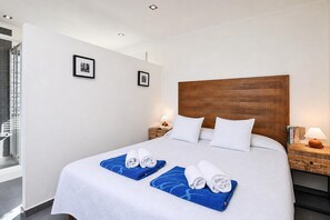 Une chambre d’hôtel avec un grand lit, deux tables de chevet, une tête de lit en bois et deux tableaux encadrés accrochés au mur.