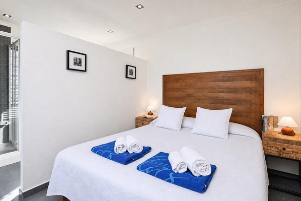 A hotel room with a large bed, two bedside tables, a wooden headboard, and two framed pictures on the wall.