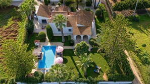 Ein Wohnhaus mit Pool, Gartenmöbeln und einem gepflegten Garten.