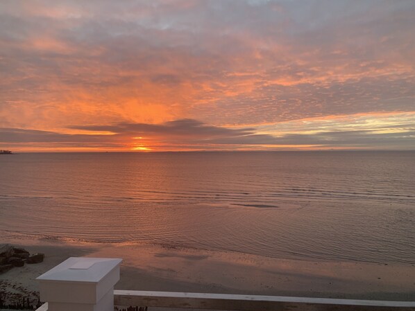 A sunset over a calm sea with a clear horizon. - Luxurious, Direct Waterfront Home with Private Beach (Milford)