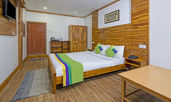 A wooden-framed bed with a colorful blanket, a wooden nightstand with a phone, a wooden wardrobe, and a wooden wall panel.