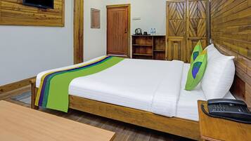 Een net opgemaakt bed met een kleurrijke deken, een bedtelefoon en een houten nachtkastje.