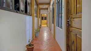 Un pasillo con plantas en macetas, puertas de madera y suelo de baldosas.