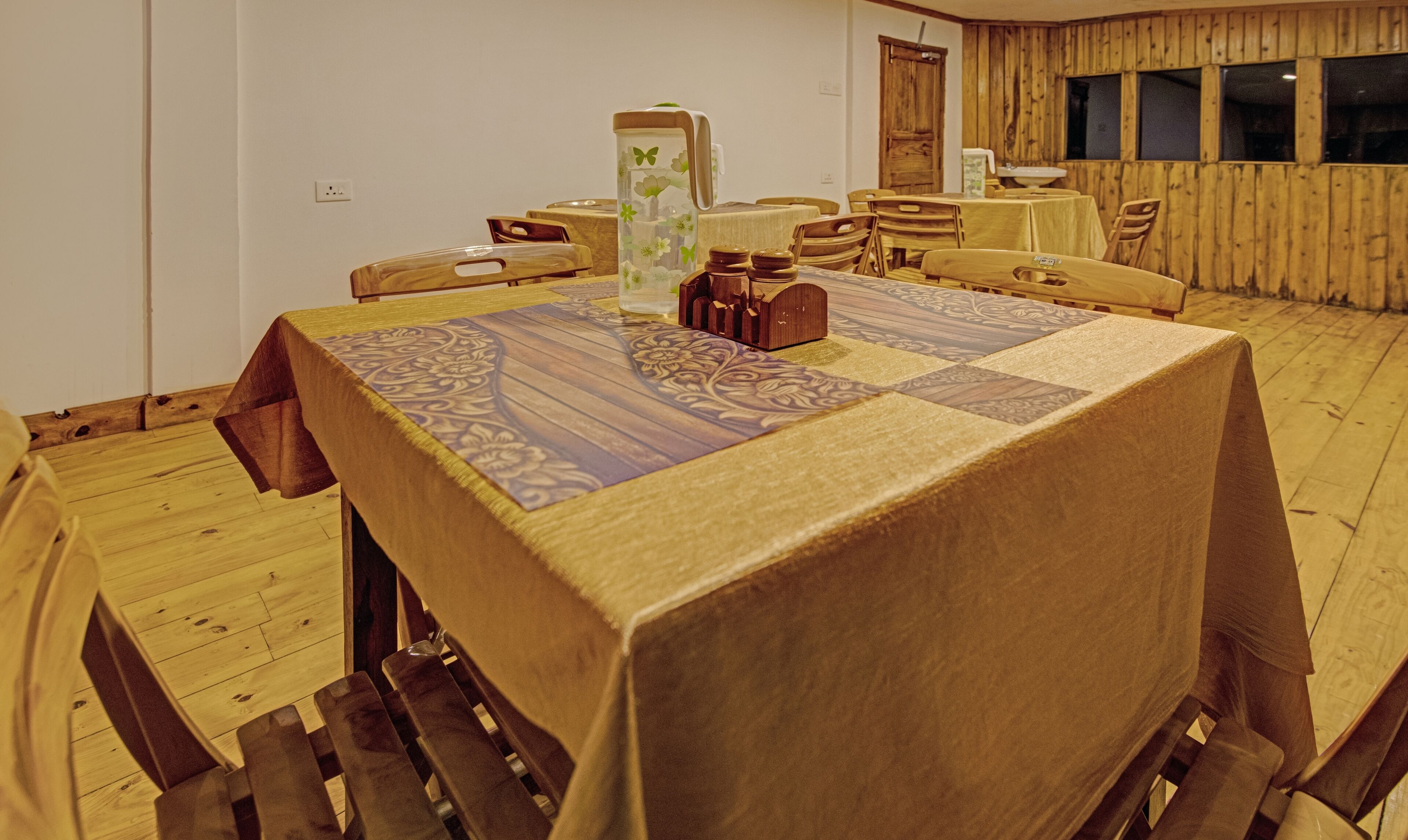 Un comedor con una mesa cubierta por un mantel estampado, rodeado de sillas de madera.