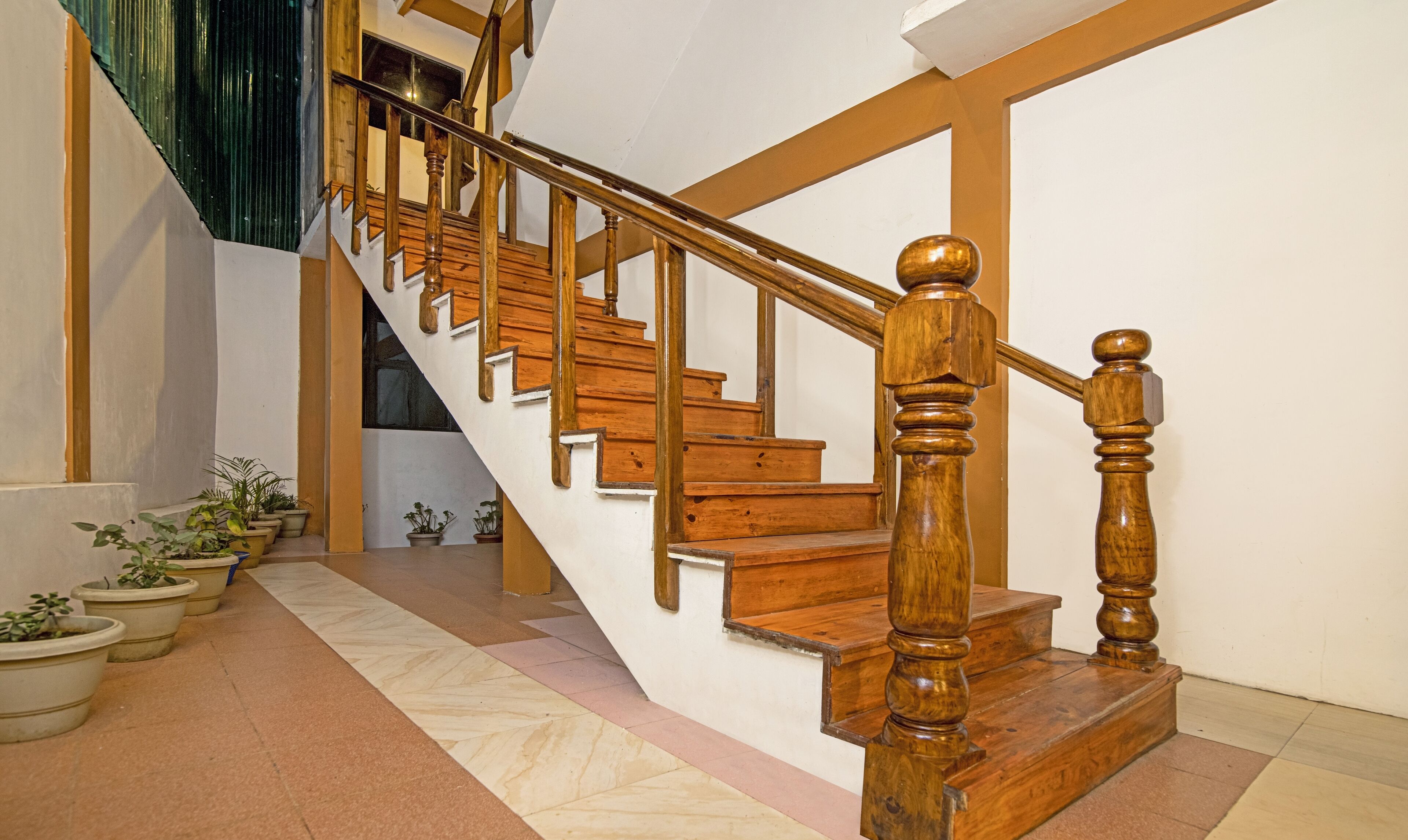 Una escalera de madera con barandilla que sube a un piso superior.