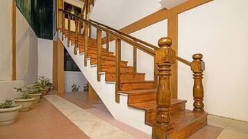 Una escalera de madera con barandilla que sube a un piso superior.