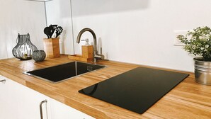 A kitchen with a black countertop, a sink, and a wooden cabinet. - Private spa with sauna and whirlpool in an idyllic setting | 10 min from Rothenburg o.d.T. (Schrozberg)