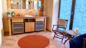 A bathroom with a wooden vanity, a large mirror, a sink, and a toilet. There is a chair and a table with a candle. - Private spa with sauna and whirlpool in an idyllic setting | 10 min from Rothenburg o.d.T. (Schrozberg)