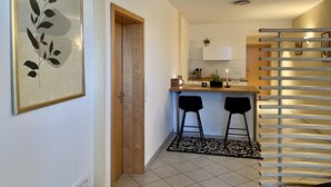 A modern kitchen with two bar stools, a wooden door, and a framed artwork on the wall. - Private spa with sauna and whirlpool in an idyllic setting | 10 min from Rothenburg o.d.T. (Schrozberg)