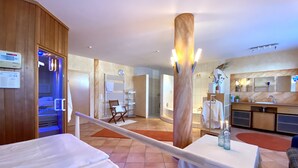 A hotel room with a bed, a massage chair, a small table with a bottle, a towel rack, and a shower area. - Private spa with sauna and whirlpool in an idyllic setting | 10 min from Rothenburg o.d.T. (Schrozberg)