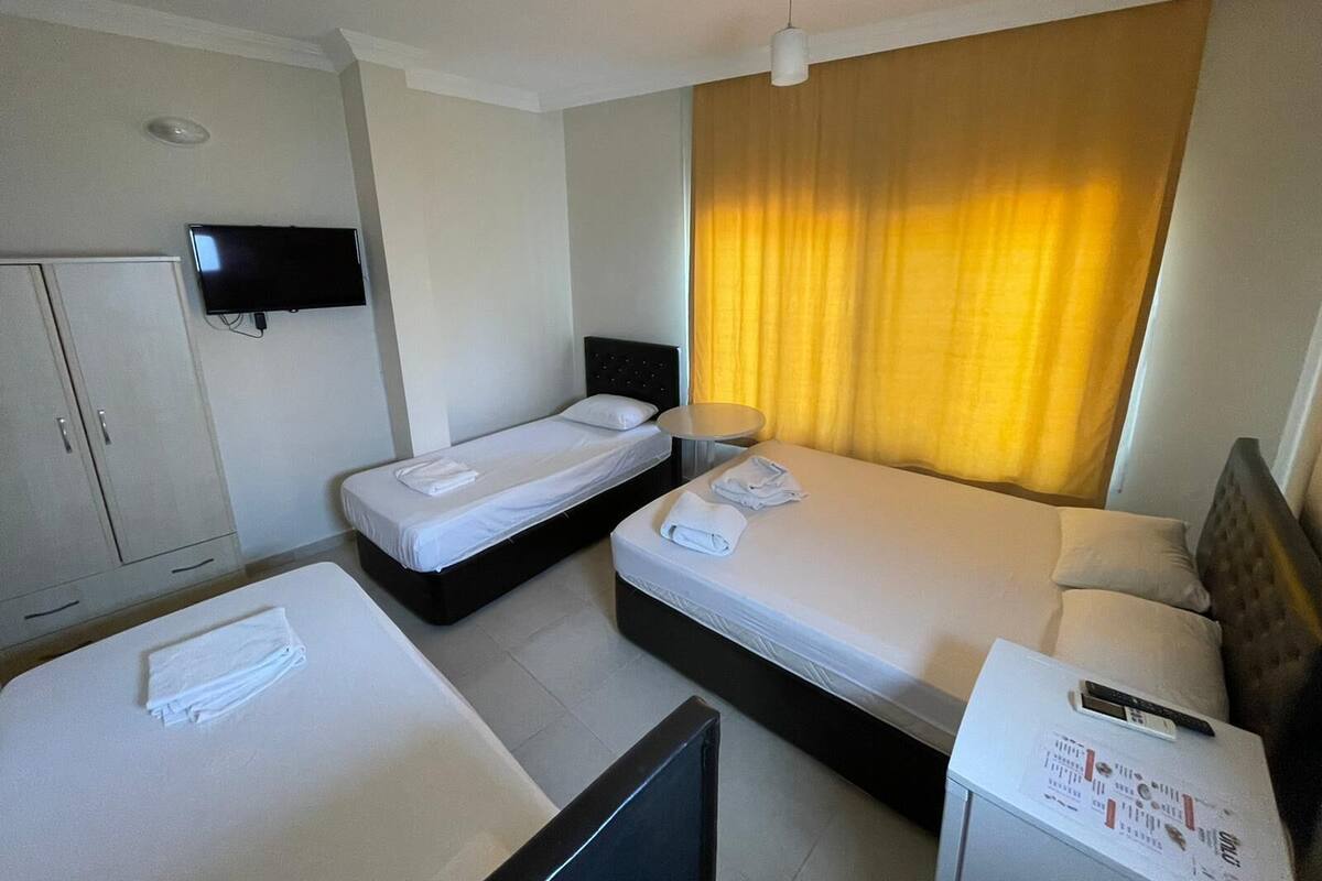 Een hotelkamer met twee eenpersoonsbedden, een aan de muur bevestigde televisie, een bureau met een lamp en een kledingkast.