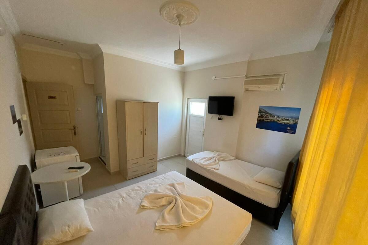 Hotelkamer met een bed, bureau, kledingkast, televisie en een raam met gordijnen.