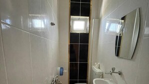 Une petite salle de bain avec des carreaux blancs, des toilettes, un lavabo et une douche.