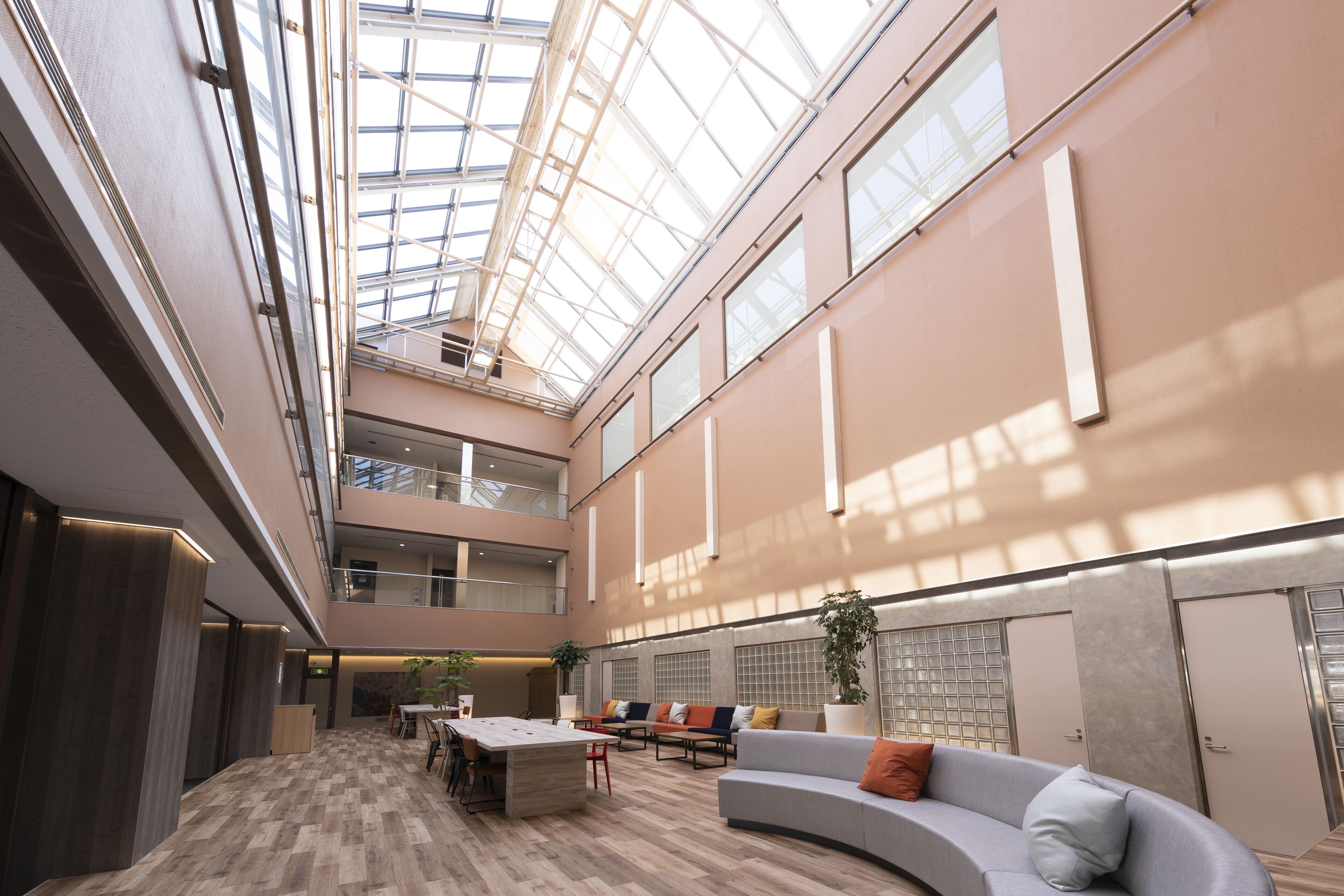 A spacious atrium with a high ceiling, a central seating area with a sofa and chairs, and a dining table with chairs.