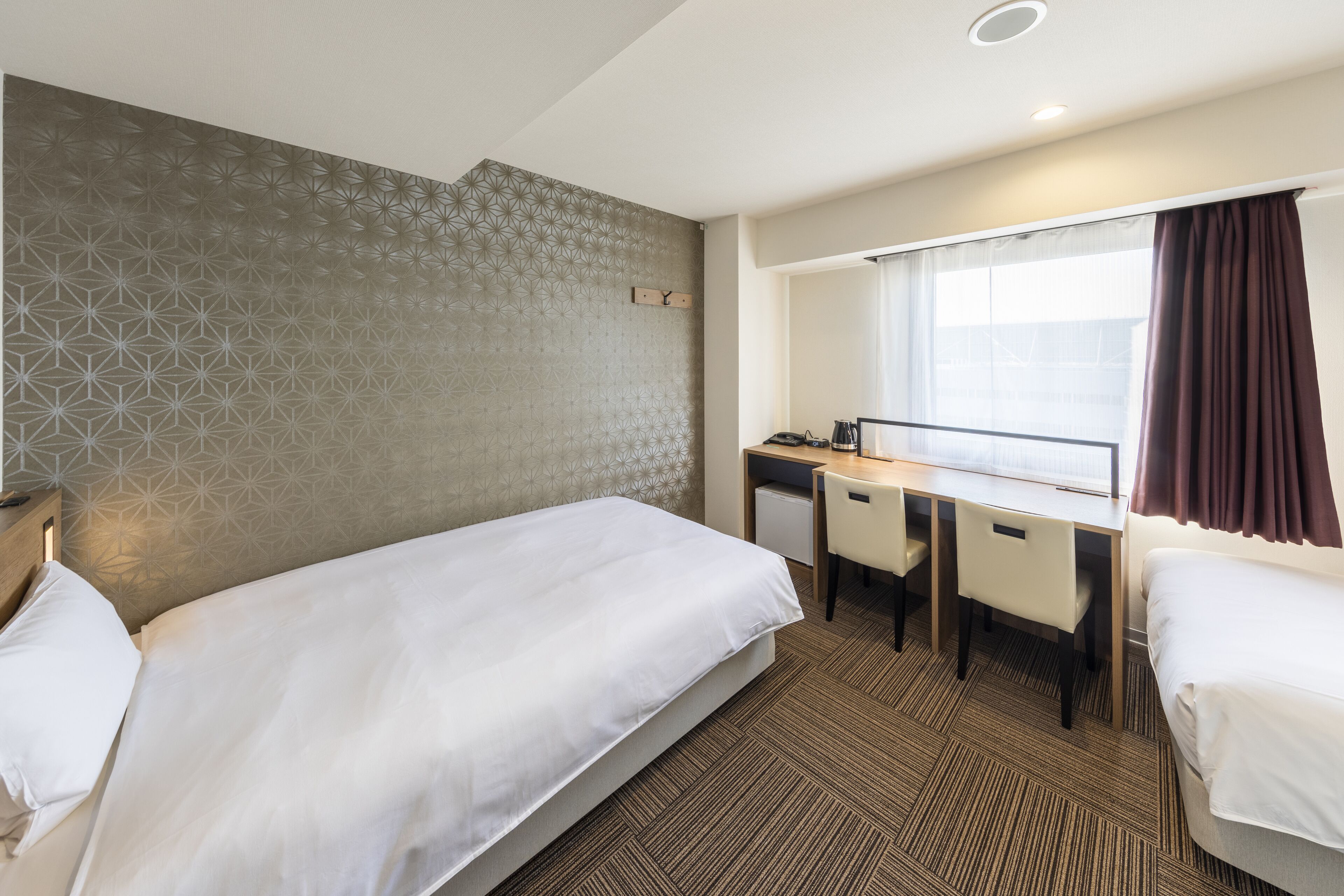 Une chambre d’hôtel avec un lit, un bureau et une chaise.