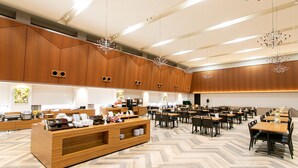 Un hall d’hôtel spacieux, doté d’un comptoir d’accueil central, de nombreuses tables et de lustres modernes.