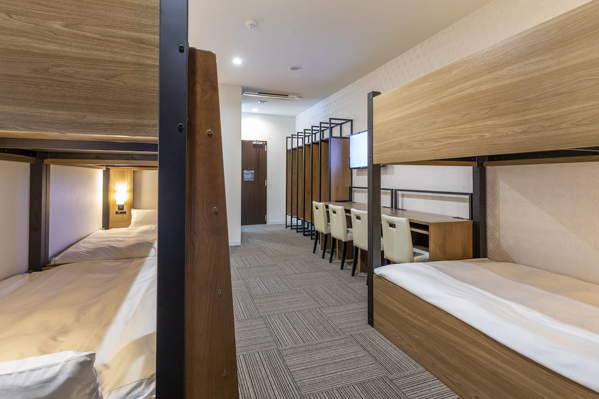 Habitación de hotel con literas, un escritorio y una silla.
