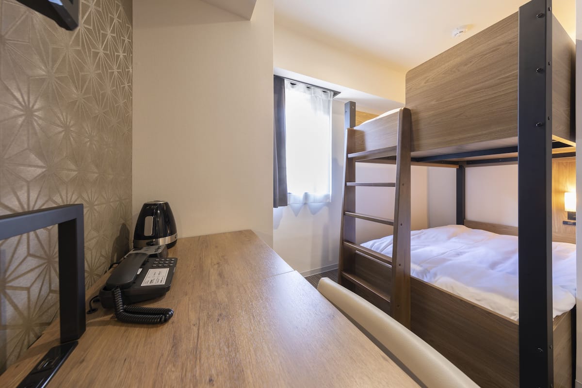 Habitación con literas, un escritorio y teléfono.