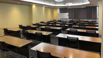 A conference room with multiple tables and chairs, a whiteboard, and a large window with curtains.