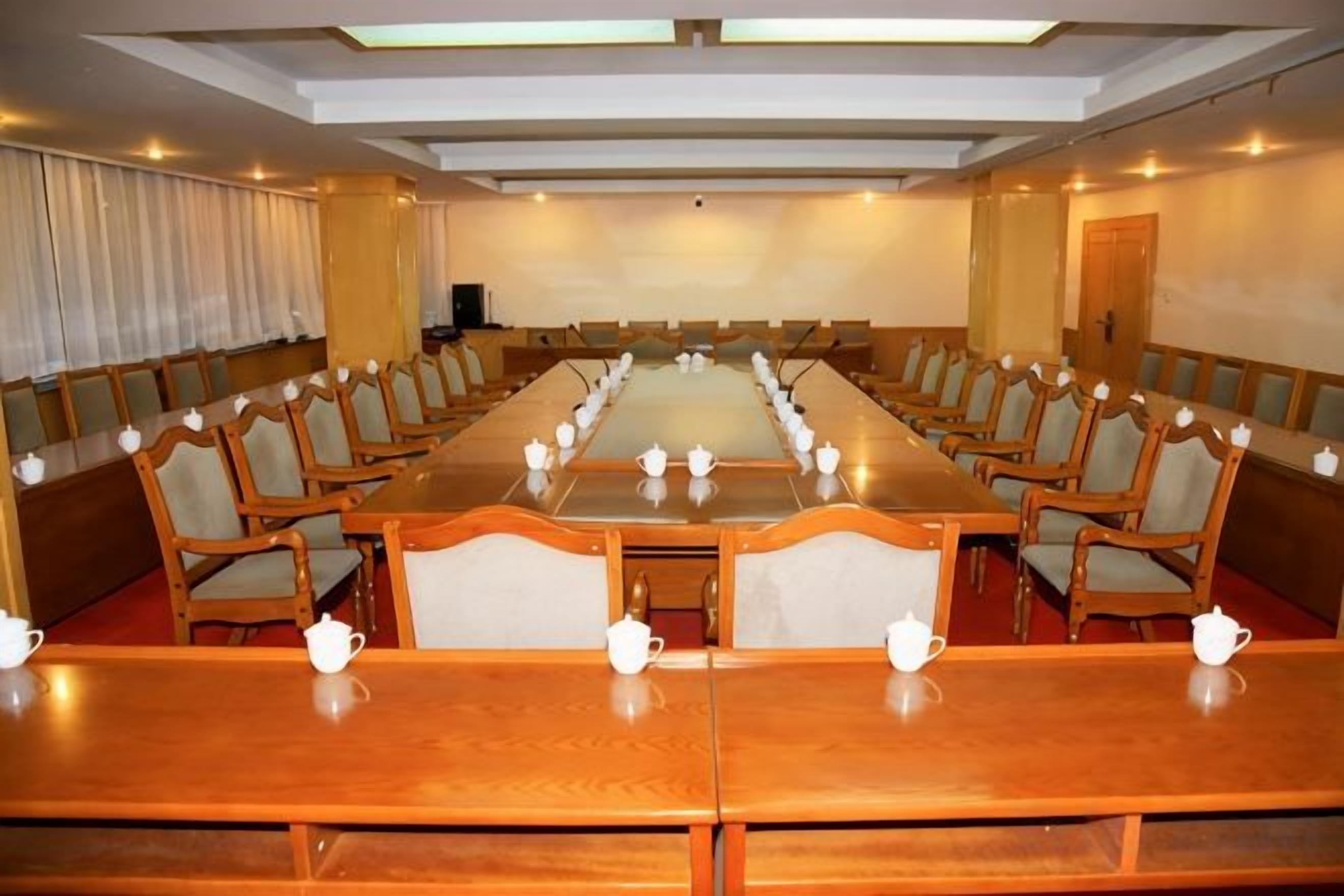 A conference room with a long table, chairs, and teapots.