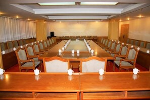 Un salón de conferencias con una larga mesa, sillas y teteras.