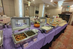 Una mesa de buffet con varios recipientes de comida y una decoración central con una calabaza.
