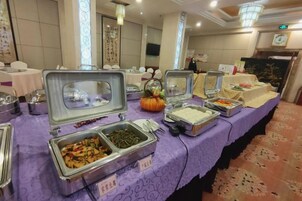 Una mesa de buffet con varios recipientes de comida y una decoración central con una calabaza.