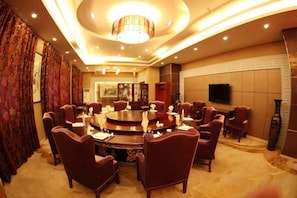 A conference room with a round table, multiple chairs, a chandelier, and a television on the wall. - Tianma Hotel (Wuwei)