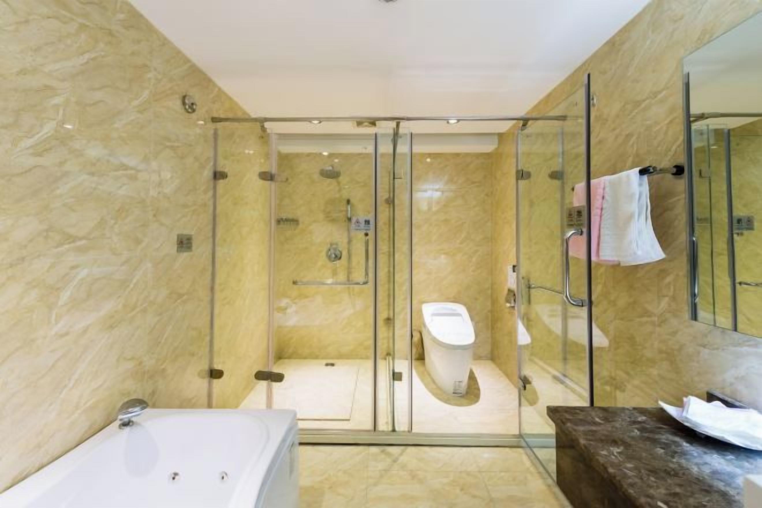 A modern bathroom with a glass-enclosed shower, a white toilet, and a bathtub.