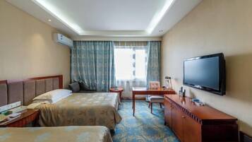 Habitación de hotel con dos camas, un escritorio, una silla, un televisor y un aire acondicionado.