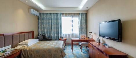Habitación de hotel con dos camas, un escritorio, una silla, un televisor y un aire acondicionado.