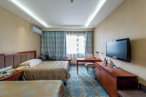 A hotel room with two beds, a desk, a chair, a television, and an air conditioning unit. - Tianma Hotel (Wuwei)