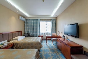 Habitación de hotel con dos camas, un escritorio, una silla, un televisor y un aire acondicionado.