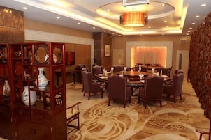 Un comedor de hotel con mesas redondas, sillas y una pared decorativa con espejos.