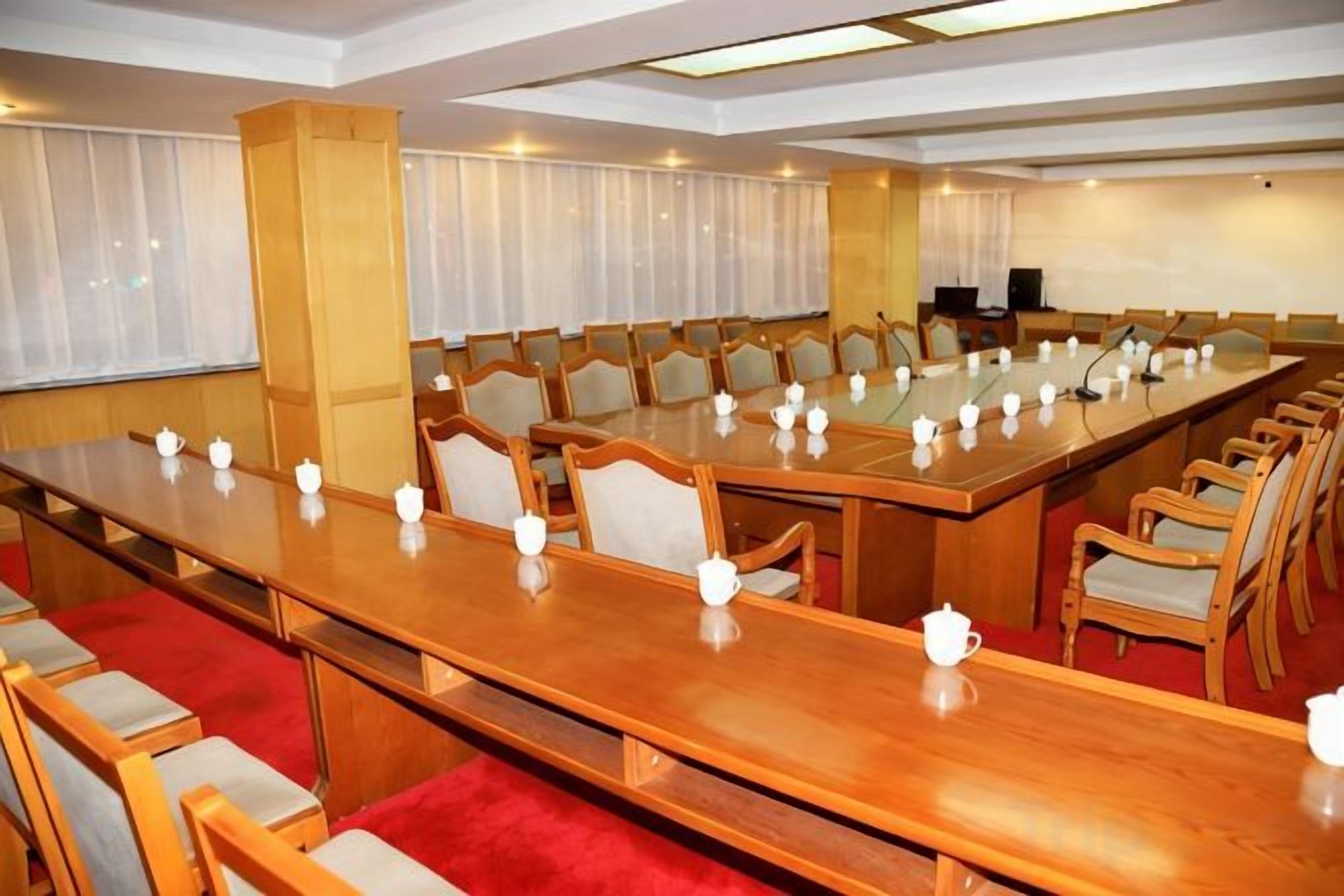 A conference room with a long table, chairs, and a projector screen.